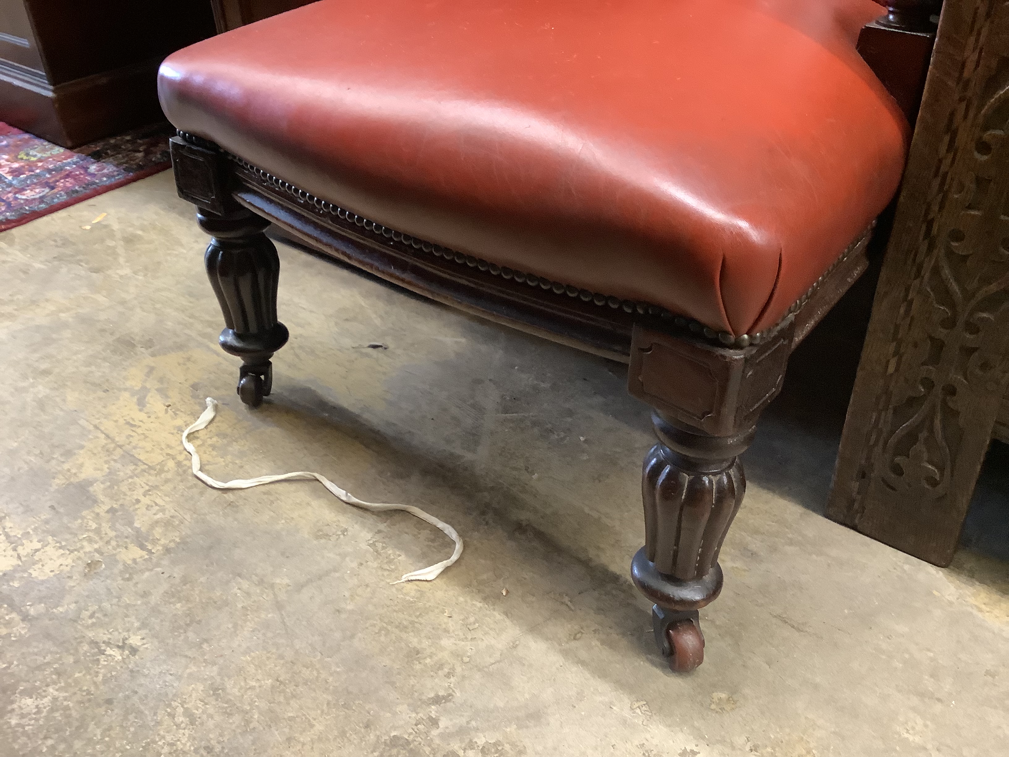 A Victorian mahogany easy chair, upholstered in buttoned red hide